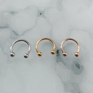 Pu&ograve; includere: Tre anelli a forma di ferro di cavallo con estremit&agrave; a sfera. Gli anelli sono argentati, dorati e oro rosa.