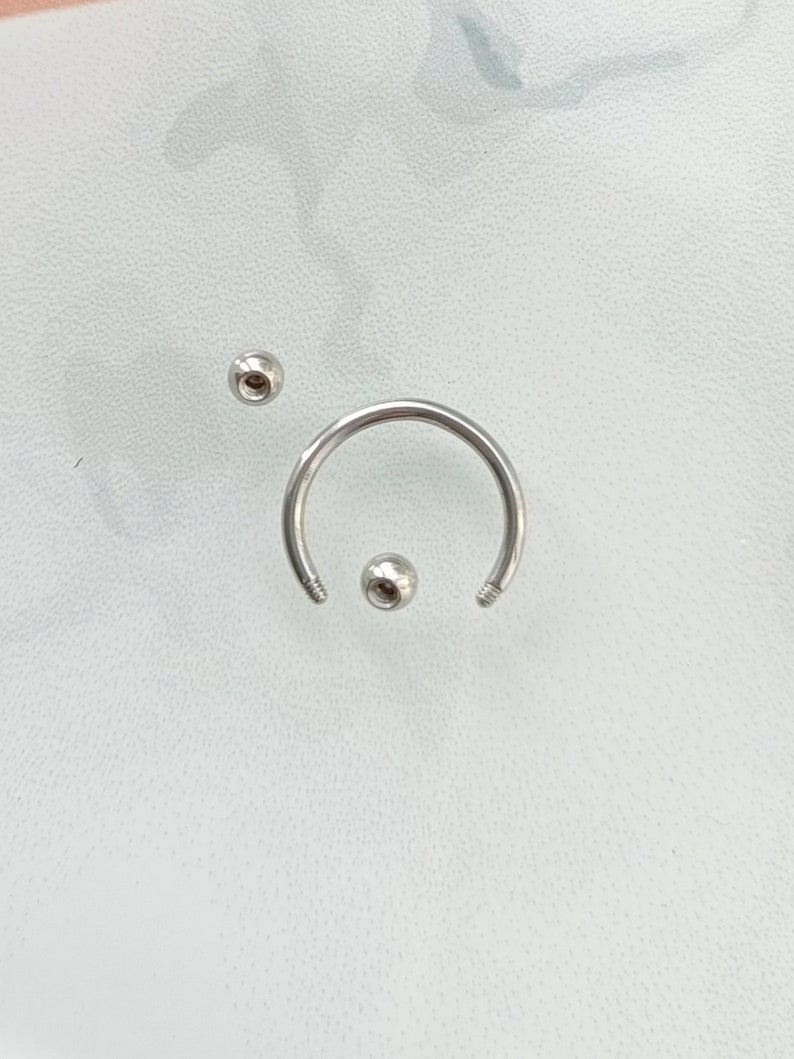 Pu&ograve; includere: Un set di gioielli per il corpo in argento con una barra circolare e due estremit&agrave; a sfera.