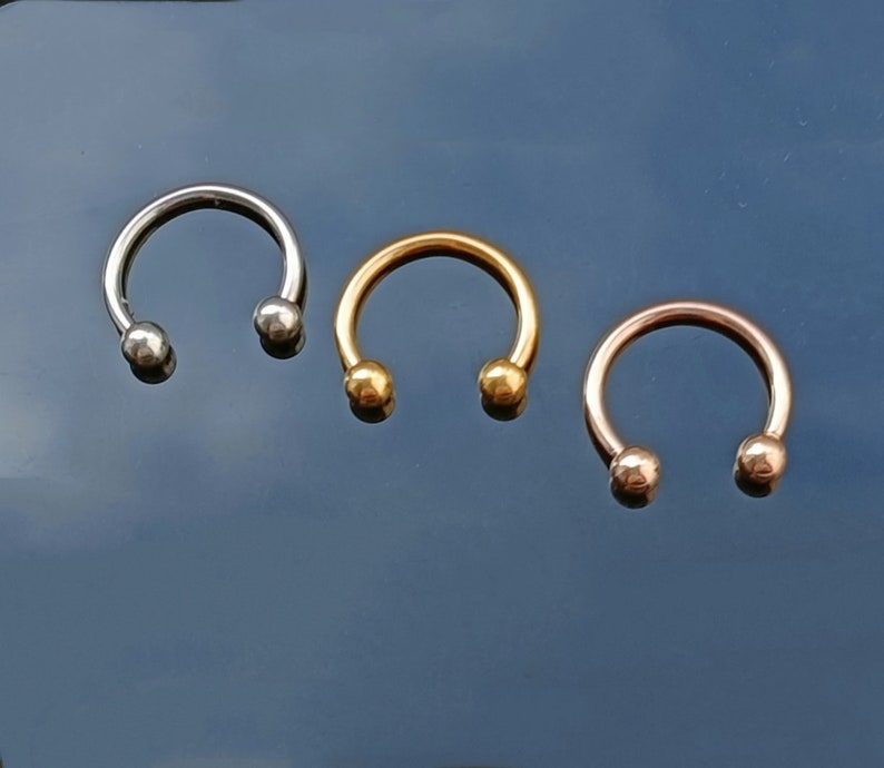 Pu&ograve; includere: Tre anelli a forma di ferro di cavallo con estremit&agrave; a sfera. Gli anelli sono argentati, dorati e oro rosa.