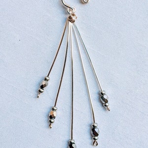 Puede incluir: Pendiente de plata con cierre de gancho y cinco hilos de alambre de plata con cuentas de vidrio facetadas plateadas. Las cuentas tienen un diámetro de 4 mm. Cuentas de vidrio facetadas plateadas; 4 mm