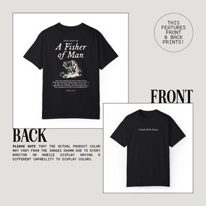 May include: Black t-shirt with a white graphic print of a fish and the text "Jesus Made Me A Fisher of Man". The back of the shirt has the text "I Catch He Cleans" printed in white.
