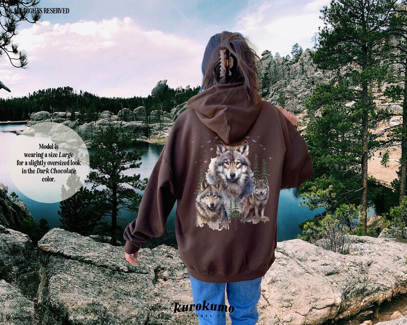 May include: A brown hooded sweatshirt with a graphic print of three wolves on the back. The sweatshirt is slightly oversized and has a dark chocolate color.