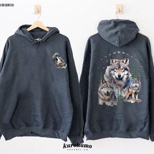 May include: A dark gray hooded sweatshirt with a wolf howling at the moon graphic on the front and a group of wolves in a forest scene on the back.