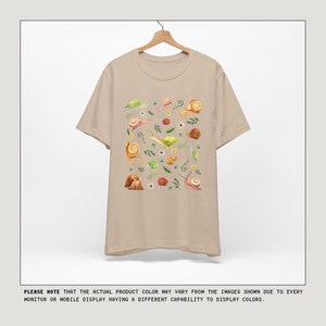 May include: A beige t-shirt with a print of snails, leaves, and flowers. The shirt has short sleeves and a crew neck.