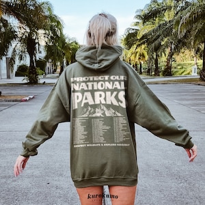 May include: Olive green hoodie with the text "PROTECT OUR NATIONAL PARKS" and a mountain graphic on the back. Below the text are the names of several national parks. The phrase "RESPECT WILDLIFE & EXPLORE SENSIBLY" is printed at the bottom.