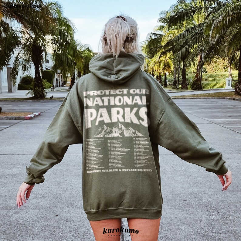 May include: Olive green hoodie with the text "PROTECT OUR NATIONAL PARKS" and a mountain graphic on the back. Below the text are the names of several national parks. The phrase "RESPECT WILDLIFE & EXPLORE SENSIBLY" is printed at the bottom.