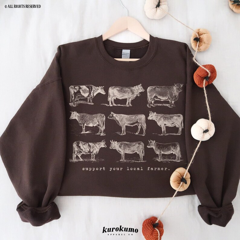May include: A brown sweatshirt with a vintage illustration of cows and the text "support your local farmer."
