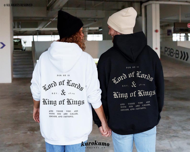 May include: Two people wearing black and white hooded sweatshirts with the text "For He Is Lord of Lords & King of Kings" printed on the back. The text is in a gothic font.
