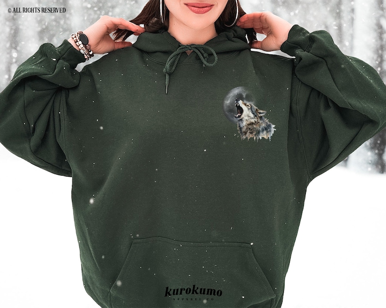 May include: A dark green hooded sweatshirt with a wolf howling at the moon graphic on the front. The graphic is in shades of gray and white.