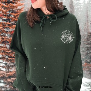 May include: Dark green hoodie with a drawstring hood and a circular graphic on the chest that reads "Protect Our National Parks." The hoodie has a relaxed fit and long sleeves. The brand name "kurokumo" is printed at the bottom.
