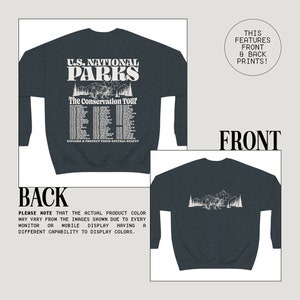 May include: Dark navy blue sweatshirt with a front graphic featuring "U.S. National Parks" text, a bear, mountains, and tour dates. The back has a matching graphic. The text "Explore & Protect Their Natural Beauty" is also included.