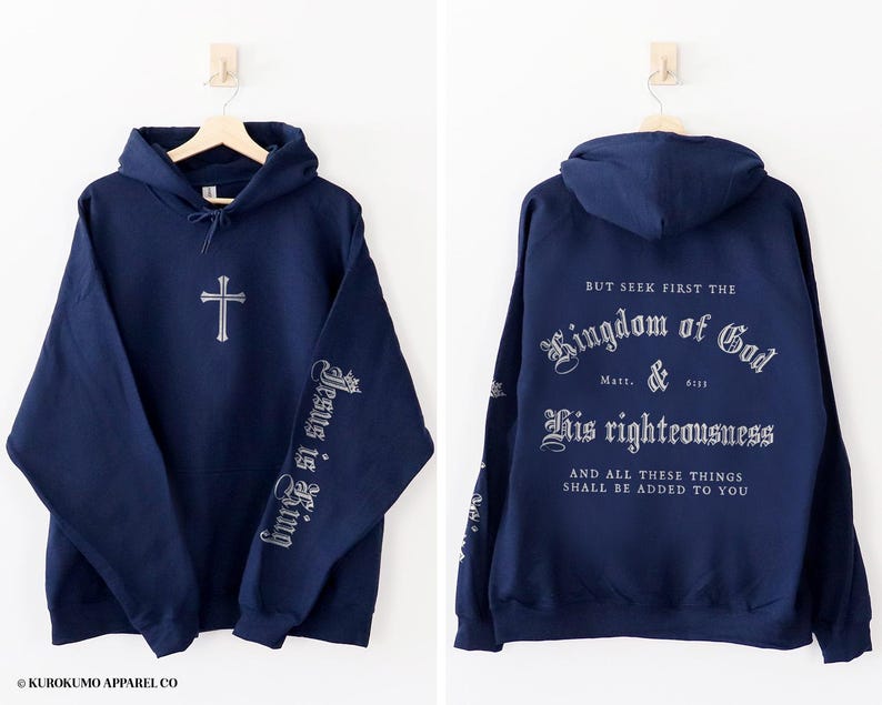 Op de afbeelding: Een marineblauw hoodie met de tekst "BUT SEEK FIRST THE Kingdom of God Matt. 6:33 His righteousness AND ALL THESE THINGS SHALL BE ADDED TO YOU" op de rug en "Jesus is King" op de linkermouw.