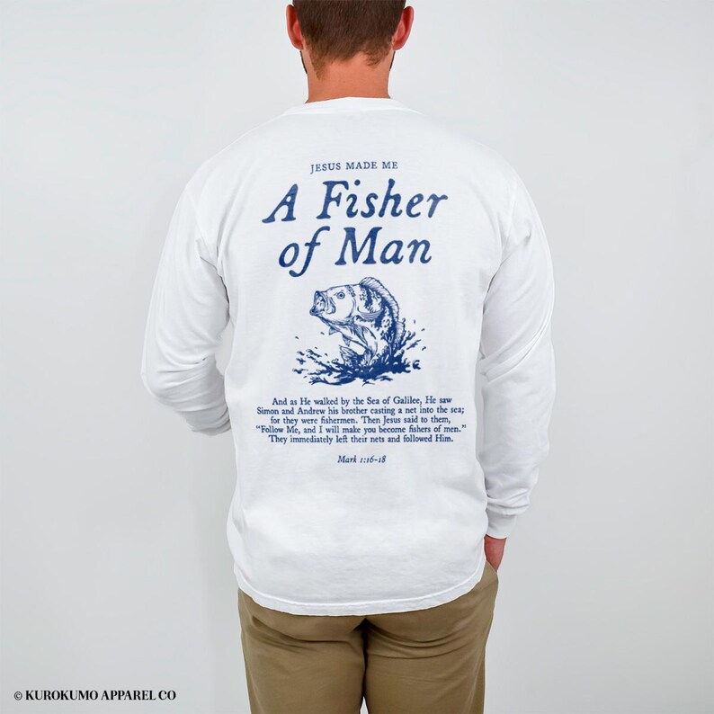 May include: White long-sleeved shirt featuring blue text and a fish illustration. The text says "JESUS MADE ME A Fisher of Man" with a Bible verse underneath. A casual style shirt.