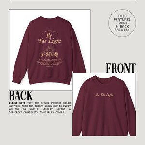 May include: Burgundy sweatshirt with a front print that says "Be The Light" and a back print that says "In this dark world, Be The Light" with a mountain and sun graphic. The sweatshirt is made by Kurokumo Apparel Co.