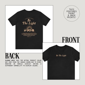 May include: Black t-shirt with a gold print on the front and back. The front print says "Be The Light" and the back print features a mountain scene with the same text.