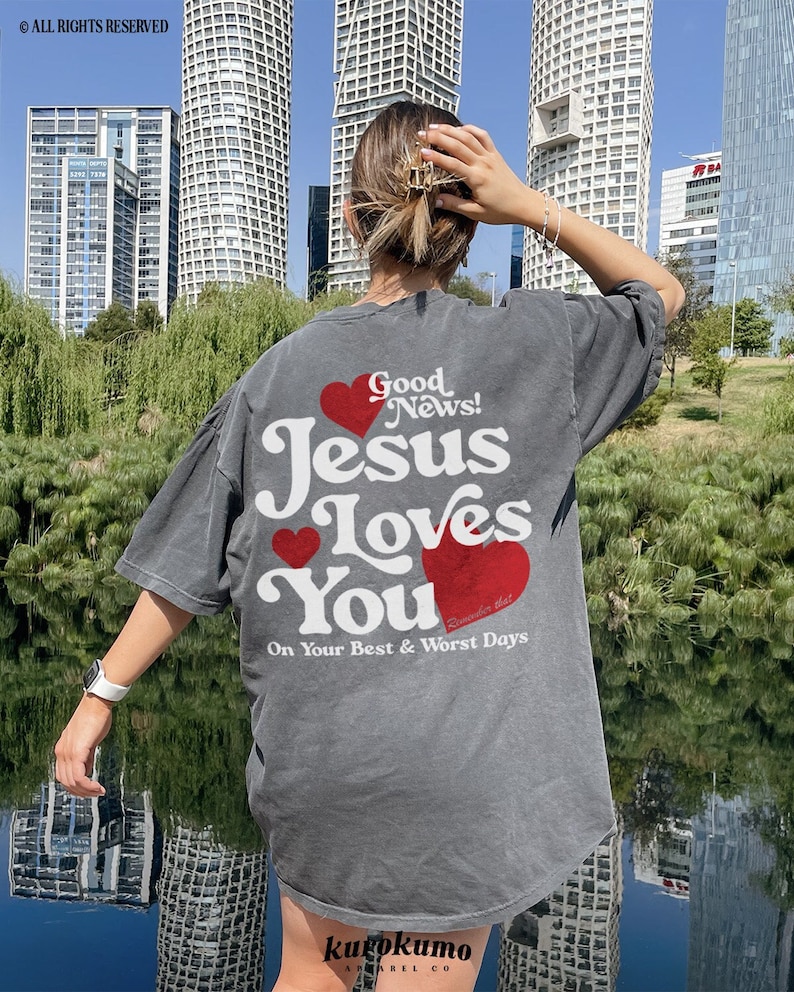 May include: A gray t-shirt with a white graphic that says "Good News! Jesus Loves You" with red hearts. The text also says "Remember this On Your Best & Worst Days".