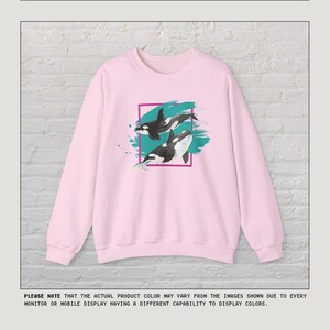 Puede incluir: Sudadera rosa con un estampado gr&aacute;fico de dos orcas nadando en agua turquesa con un efecto de pinceladas rosa y blanco. El gr&aacute;fico est&aacute; enmarcado en un cuadrado rosa.