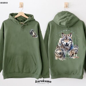 May include: A green hooded sweatshirt with a wolf howling at the moon graphic on the front and a group of wolves in a forest scene on the back.