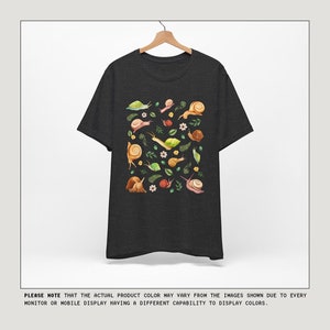 May include: A dark heather grey t-shirt with a colorful graphic print of snails and leaves. The text "COLOR OPTIONS" is at the top of the image and the text "MESSAGE US IF INTERESTED IN ANOTHER COLOR NOT SHOWN" is at the top right of the image. The text "kurokumo APPAREL CO" is at the bottom of the image.