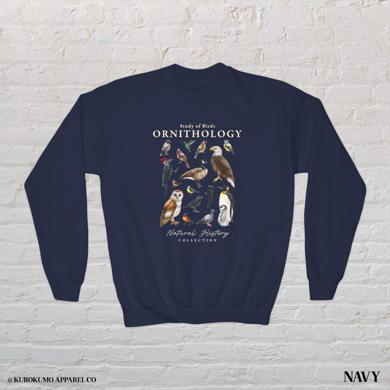 May include: Navy blue sweatshirt featuring a detailed illustration of various bird species. The design includes the text "Study of Birds ORNITHOLOGY Natural History Collection". The sweatshirt is a comfortable, long-sleeved garment.