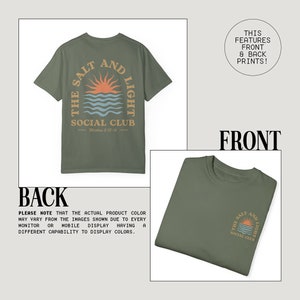 May include: A green t-shirt with a graphic print on the back that says "The Salt and Light Social Club" with a sunset and waves design. The front of the shirt has a smaller version of the same graphic print.