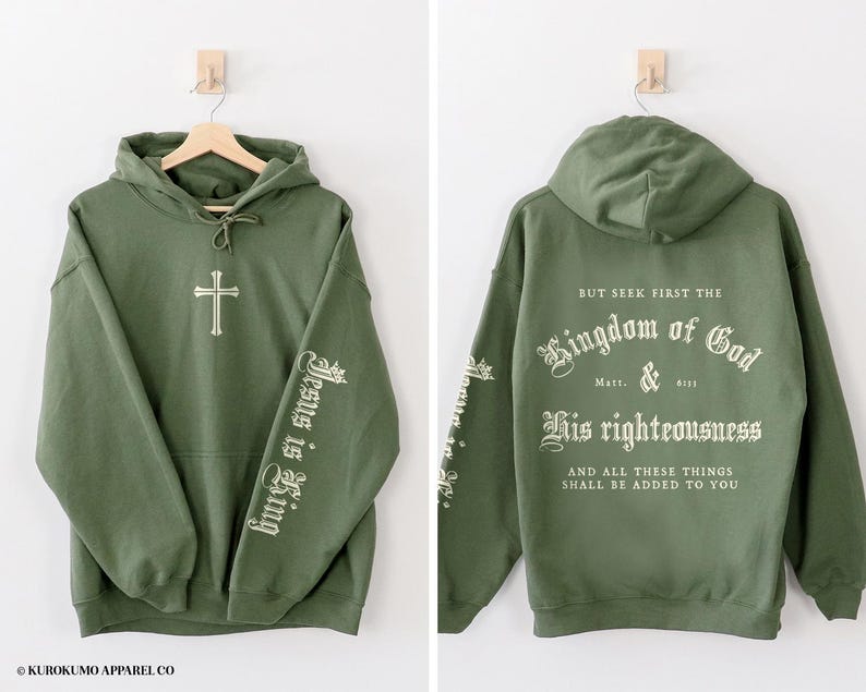 Op de afbeelding: Een groene hoodie met de tekst "Jesus is King" op de ene mouw en "But seek first the Kingdom of God & His righteousness And all these things shall be added to you" op de andere mouw.