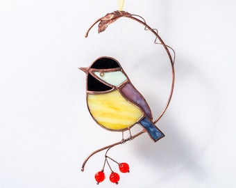 May include: A stained glass bird with yellow, blue, black, and white glass pieces, perched on a copper wire branch with red glass berries.
