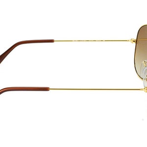 Puede incluir: Gafas de sol aviador doradas con lentes de degradado marr&oacute;n. Las gafas tienen puntas de patillas de pl&aacute;stico marr&oacute;n.