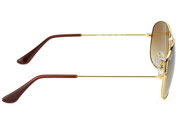 Puede incluir: Gafas de sol aviador doradas con lentes de degradado marr&oacute;n. Las gafas tienen puntas de patillas de pl&aacute;stico marr&oacute;n.