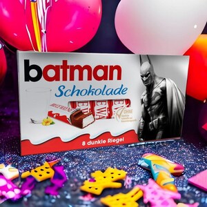 Könnte beinhalten: Eine rechteckige Schachtel Batman Schokolade mit einer schwarz-weißen Batman-Illustration, einem Glas Milch und einem ausgepackten Riegel. Die Verpackung zeigt den Text Batman Schokolade sowie die Aufschrift 8 dunkle Riegel.