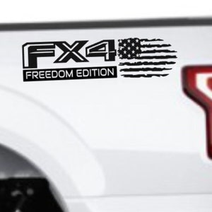 May include: Black FX4 Freedom Edition decal with a distressed American flag design. The decal is applied to the white body of a truck, near the taillight.