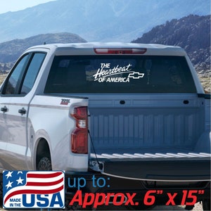 May include: White decal with the text "The Heartbeat of America" and a Chevrolet logo, displayed on a truck's rear window. The decal is approximately 6 inches by 15 inches. Includes a "Made in the USA" graphic.