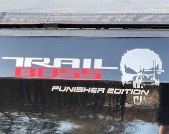 May include: A vinyl decal applied to a black surface featuring the white text TRAIL, the red text BOSS, and a white skull graphic with a cross symbol. Below the graphic, the white text reads PUNISHER EDITION in a clean, sans-serif font.