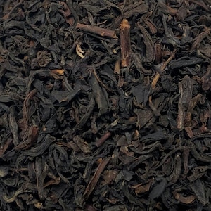 May include: Loose black tea leaves with a dark brown hue. The tea leaves are dried and ready to be brewed.