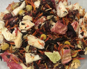 May include: A mix of dried fruit, flowers, and tea leaves. The fruit pieces are red, orange, and white. The flowers are yellow and white. The tea leaves are dark brown.