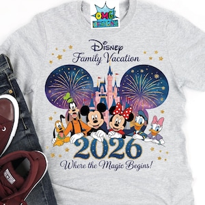 Puede incluir: Una camiseta gris claro con un gr&aacute;fico de Disney Family Vacation 2026 con Mickey Mouse, Minnie Mouse, Goofy, Pluto, Donald Duck y Daisy Duck frente a un castillo con fuegos artificiales. El texto dice Disney Family Vacation 2026 Where the Magic Begins.