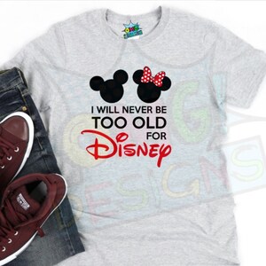 Puede incluir: Una camiseta gris con un gráfico rojo que dice "Nunca seré demasiado viejo para Disney". El gráfico también incluye una silueta negra de Mickey Mouse y Minnie Mouse.