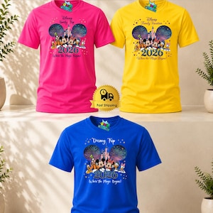 Puede incluir: Tres camisetas de manga corta y cuello redondo en rosa brillante, amarillo y azul. Cada camiseta presenta un gr&aacute;fico de personajes de Disney, un castillo, fuegos artificiales, el a&ntilde;o 2026 y el texto Disney Family Trip o Disney Trip Where the Magic Begins.