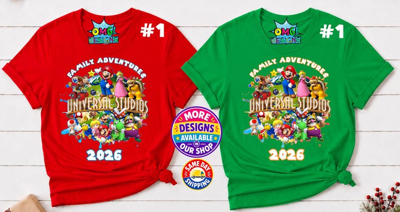 May include: A red and a green short-sleeved t-shirt, each featuring a graphic print of various video game characters, the text "FAMILY ADVENTURES UNIVERSAL STUDIOS" and "2026". The shirts include a small "OMG DESIGNS" logo at the top center.