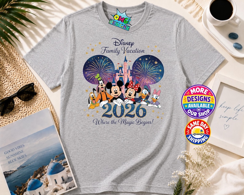 Puede incluir: Una camiseta gris jaspeado con un gr&aacute;fico de personajes de Disney que incluye a Mickey, Minnie, Goofy, Pluto, Donald y Daisy frente a un castillo con fuegos artificiales. El texto dice Disney Family Vacation 2026 Where the Magic Begins.