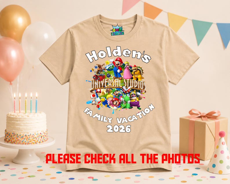 May include: A tan short-sleeved t-shirt featuring a colorful graphic of various Nintendo characters, the text "Holden's UNIVERSAL STUDIOS FAMILY VACATION 2026", and a small logo on the inner neck label. The shirt is displayed against a festive party background.