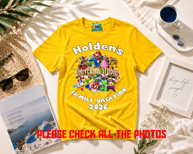 May include: A bright yellow short-sleeve t-shirt featuring a graphic of various Nintendo characters over a globe. The text reads Holden's UNIVERSAL STUDIOS FAMILY VACATION 2026. The shirt has a round neckline and a small logo on the inner collar.