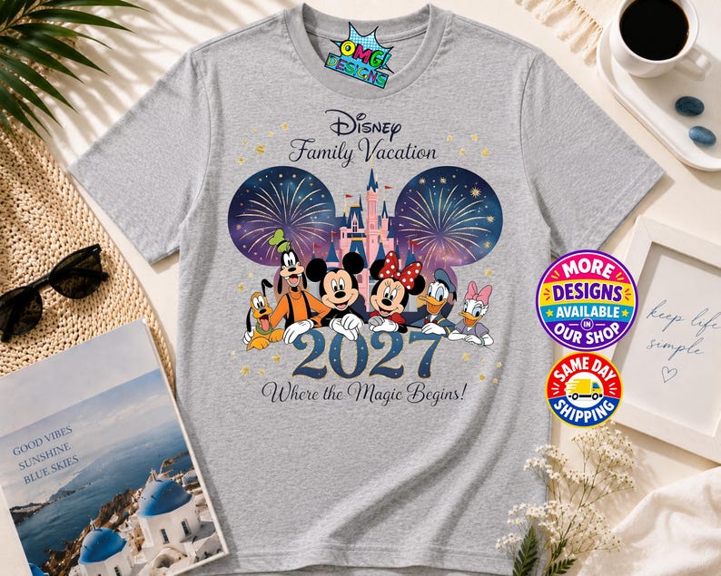 Puede incluir: Una camiseta gris jaspeado con un gr&aacute;fico de personajes de Disney que incluye a Mickey, Minnie, Goofy, Pluto, Donald y Daisy frente a un castillo y fuegos artificiales. El texto dice Disney Family Vacation 2027 Where the Magic Begins.