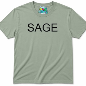 Puede incluir: Una camiseta de manga corta color verde salvia con la palabra SAGE impresa en letras may&uacute;sculas negras en el pecho. La etiqueta interior del cuello muestra el texto OMG DESIGNS en un gr&aacute;fico colorido de estilo c&oacute;mic con fondo de estrella.