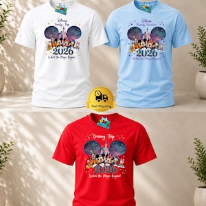 Puede incluir: Tres camisetas de manga corta y cuello redondo en blanco, azul claro y rojo. Cada camiseta presenta un gr&aacute;fico de personajes de Disney, un castillo, fuegos artificiales, el a&ntilde;o 2026 y el texto Disney Family Trip o Disney Family Vacation Where the Magic Begins.