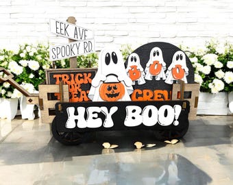 May include: A wooden wagon decorated for Halloween with a black sign that says "Hey Boo!" and a sign that says "Eek Ave Spooky Rd."  The wagon is decorated with ghosts, a pumpkin, and a sign that says "Trick or Treat Crew".