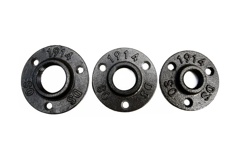 May include: Three black metal pipe flanges with a 1 1/2 inch inner diameter and three bolt holes. The flanges are marked with the number "1914" and the letters "DSS".