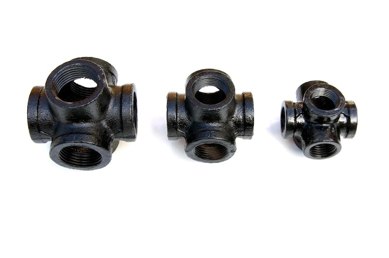 May include: Three black metal pipe fittings with six openings each. The fittings are different sizes.