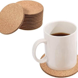 May include: A set of 12 round cork coasters stacked together. A white ceramic mug is placed on a single coaster.