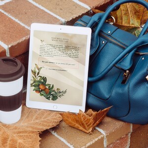 May include: A white tablet displays text and botanical illustrations, next to a teal handbag and a white travel mug with a brown lid. The tablet's screen features the words "YOU WILL HAVE WHAT YOU SAY". The scene is set on a brick surface with fallen leaves.